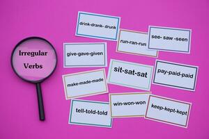 Paper Word Cards Of Irregular Verbs And Magnifying Glass Pink Background Concept Education English Vocabulary And Grammar Teaching Teaching Aid Educational Materials Photo